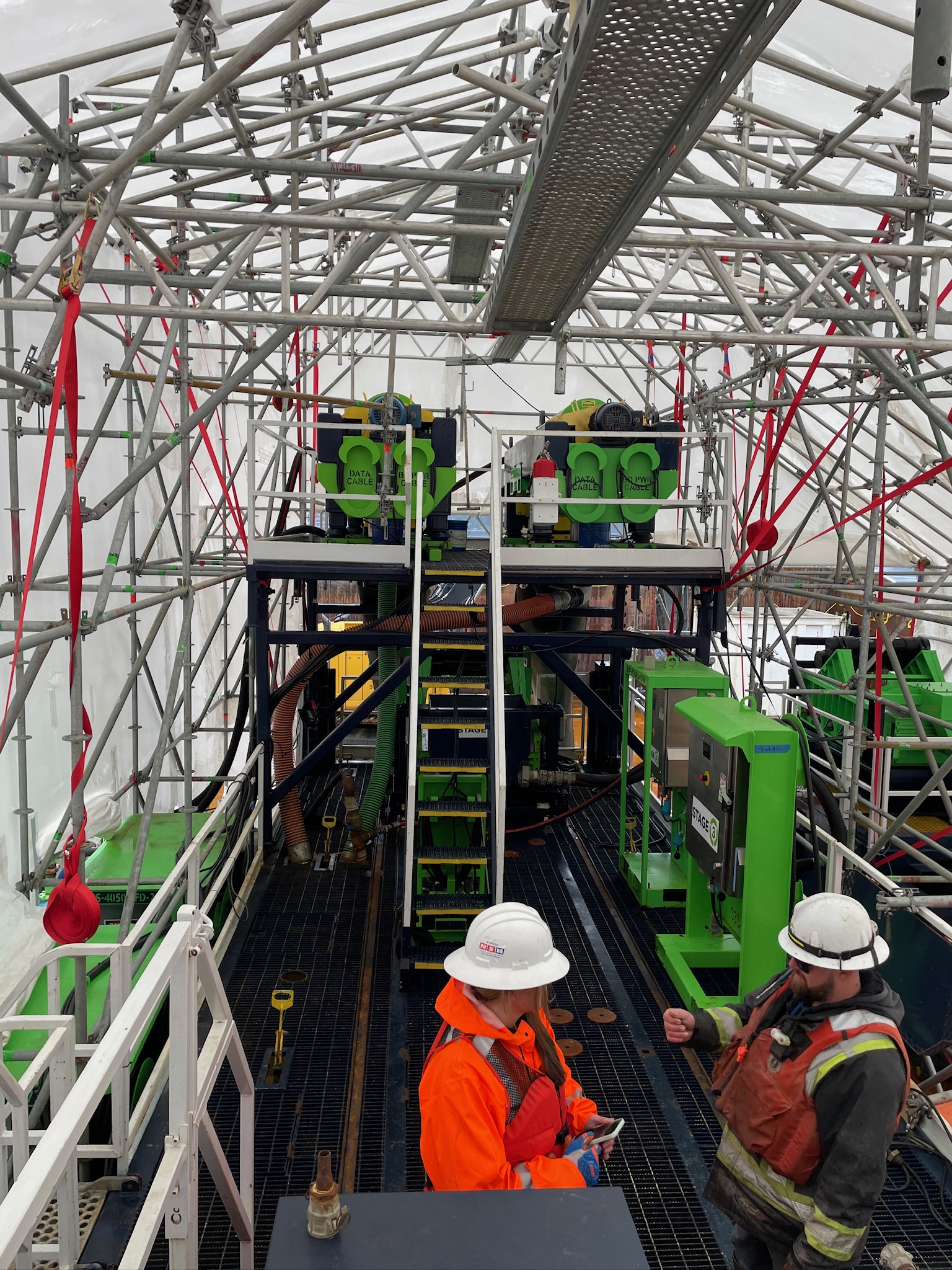 Two field technicians in protective equipment working inside a winterized system